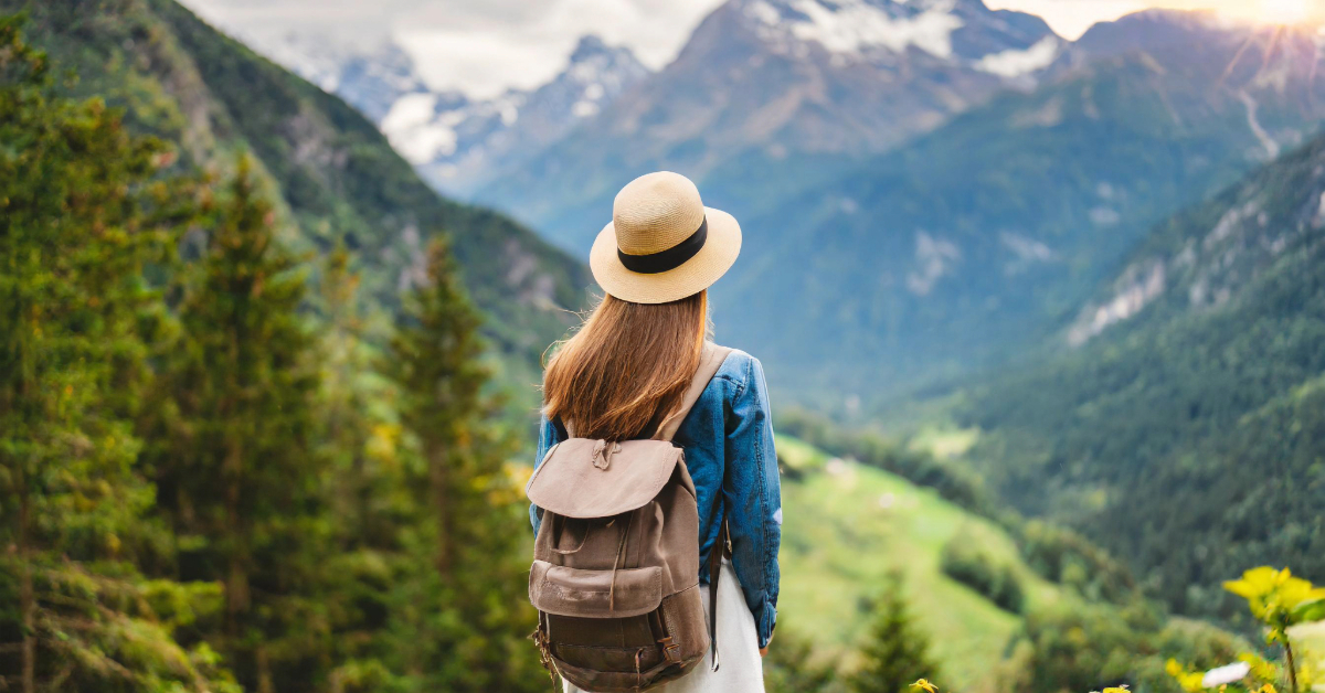 woman finding peace outdoors while hiking and looking into a mountain valley